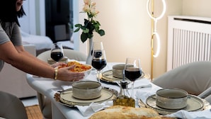 A dining table set with plates, glasses, and a loaf of bread.