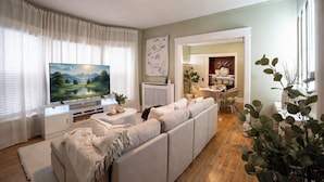 A living room with a large flat-screen TV, a sofa, a fireplace, and a dining area with chairs and a table.