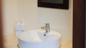 Un baño con un lavamanos blanco, un espejo y dos botellas de jabón de manos sobre la encimera.