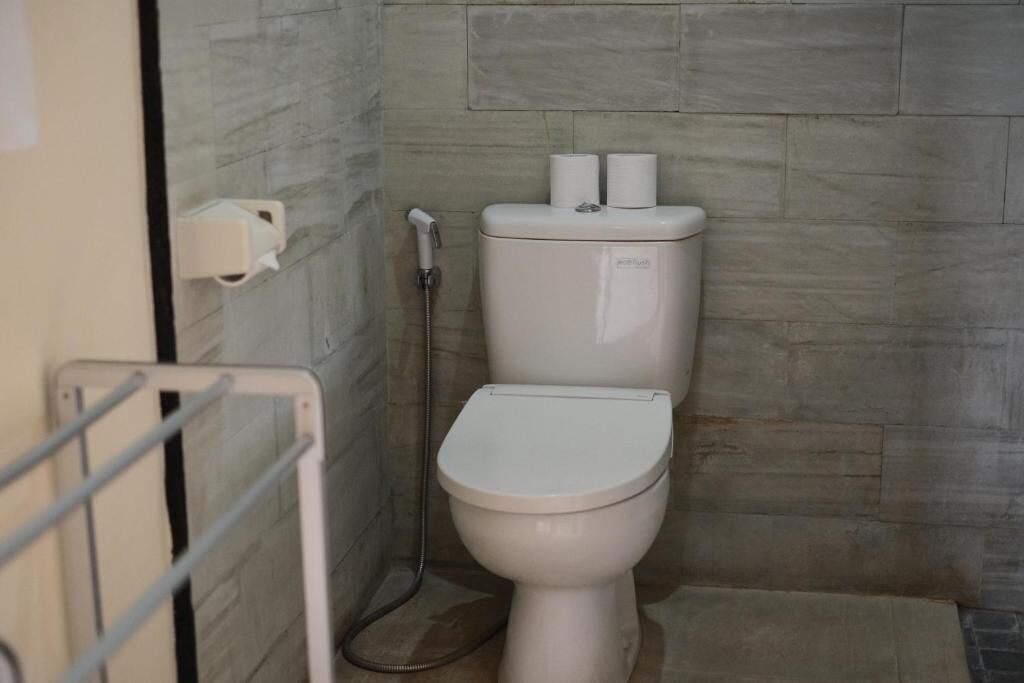 A bathroom with a toilet, a hand dryer, and a paper towel dispenser.