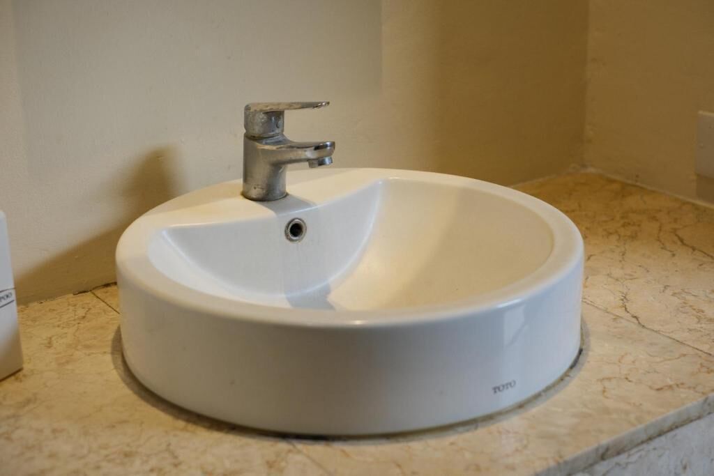 A white ceramic sink with a single faucet on a marble countertop in a bathroom.