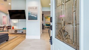 Een moderne woonkamer met een flatscreen televisie, een inlijsting tijdschrift en een deur met een decoratief glasraam.