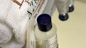 A white towel with embossed text and three bottles of cream on a table. - Posada Azeneth (Oxkutzcab)