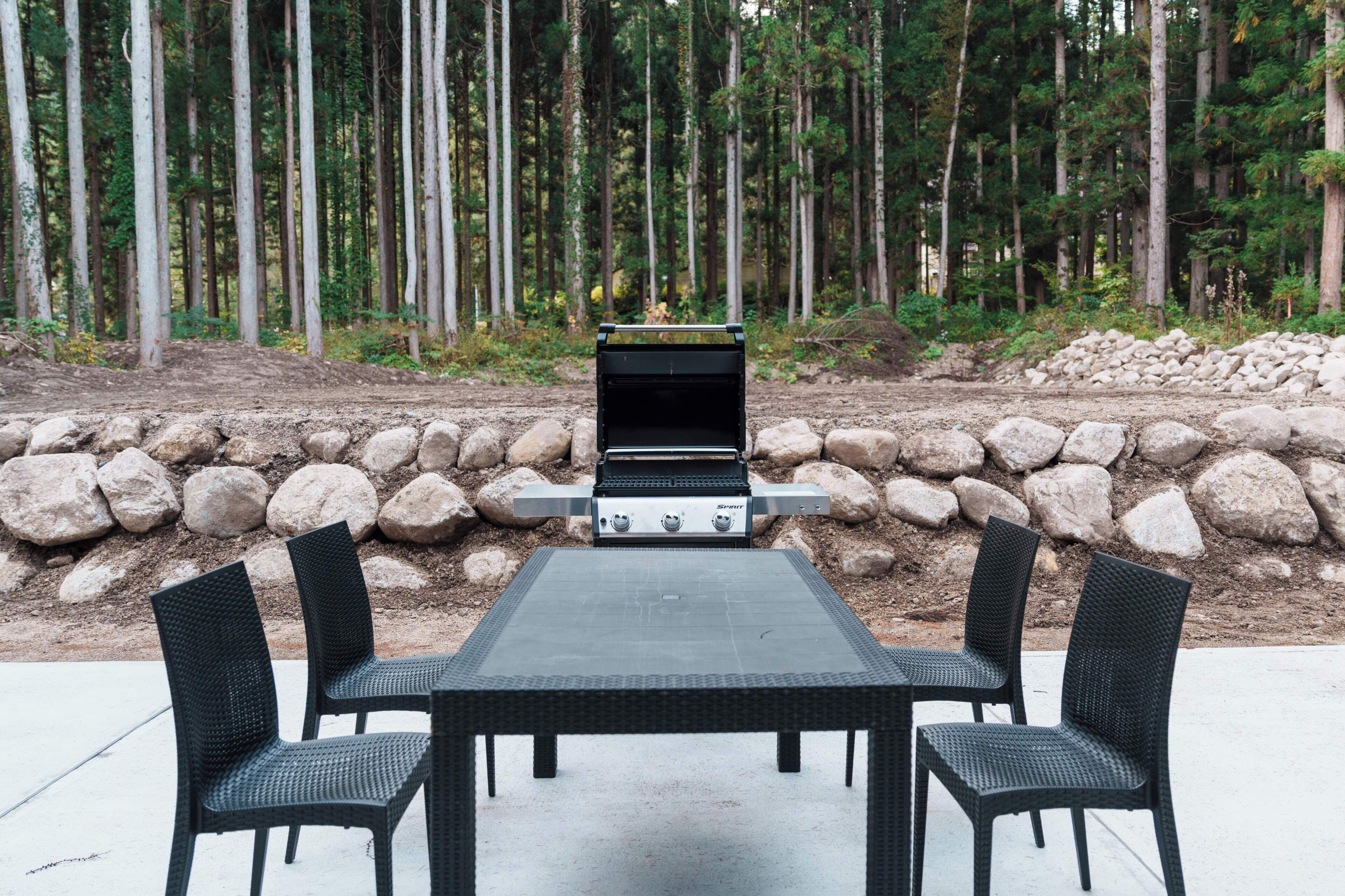 Eine Terrasse im Freien mit Grill, Tisch und Stühlen.