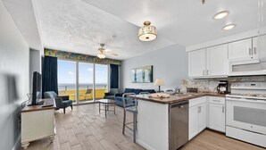 Una cucina moderna con mobili bianchi, un'isola centrale e vista all'esterno.