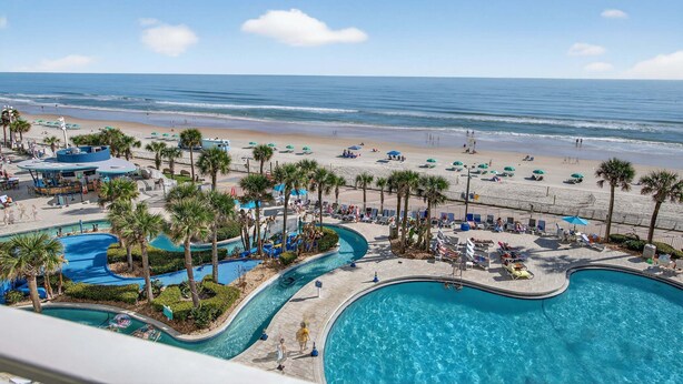 Un resort con piscina, spiaggia e palme.