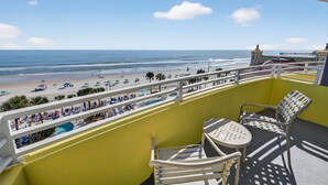 Un balcone con vista sulla spiaggia, una piscina e un edificio con una torre.