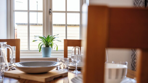 A dining table set with plates, glasses, and a potted plant. - Lovely 2 BD Home in Moreton-in-Marsh (Moreton-in-Marsh)