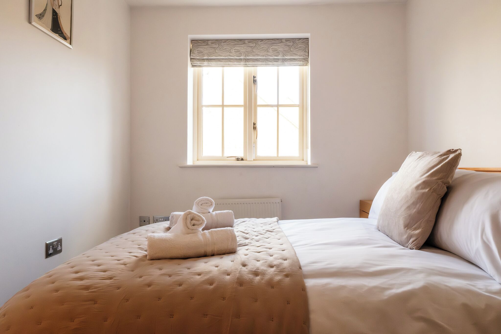 A bedroom with a bed, a window with a curtain, and a radiator.