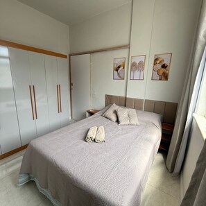 Ein Schlafzimmer mit einem Bett, einem Kleiderschrank und drei gerahmten Bildern an der Wand.