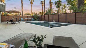 Un jardin avec une piscine, des meubles de patio et des palmiers.