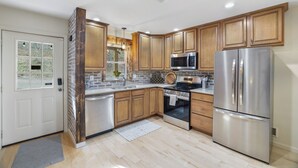 Una cucina moderna con mobili in legno, elettrodomestici in acciaio inossidabile e una finestra vista verde.