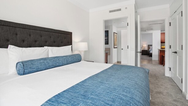 Una camera d'albergo con un letto grande, un ventilatore a soffitto e vista sul corridoio.