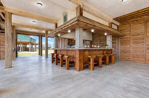 Eine Bar mit Holzhockern, einer Theke und Blick ins Freie.