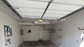 Eine Garage mit Betonboden, einer weißen Tür und einer Decke mit Metallträgern.