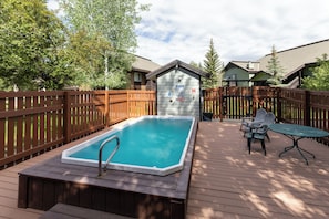 A swimming pool on a wooden deck with a small shed and a table with chairs. - Quail Run 3315 - Renovated Condo, Hot Tub, Garage, W/D (Steamboat Springs)