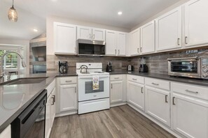 A modern kitchen with white cabinetry, a stainless steel range, a built-in microwave, and a toaster. - Quail Run 3315 - Renovated, Hot Tub, Garage, W/D + EZCancel (Steamboat Springs)