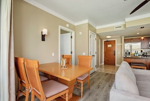A dining area with a wooden table and chairs, a kitchen in the background, and a living area with a sofa. - 3 Honua Kai Villas | Ocean Front | Sleeps 16 | Free Car w/ 6+ Nights | ML-2720 (Lahaina)
