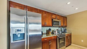 Una cocina con electrodomésticos de acero inoxidable, armarios de madera y salpicadero de azulejos.