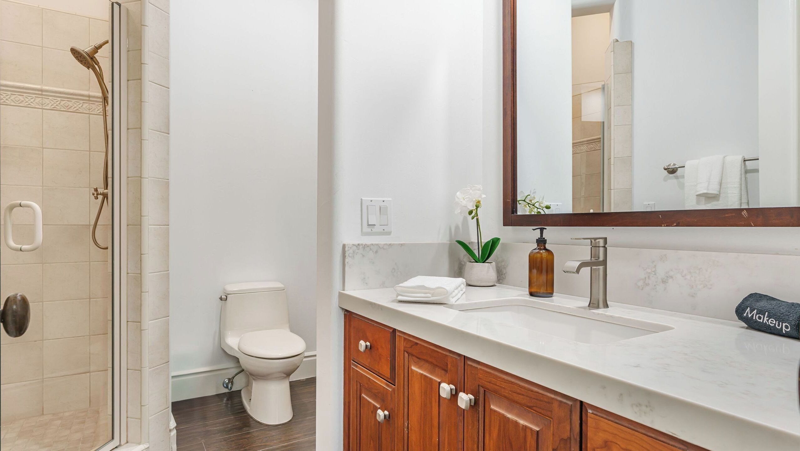 A bathroom with a shower, toilet, sink, and vanity.