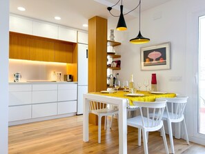 A modern kitchen with white cabinets, wooden accents, and pendant lighting. - Modern, Open-plan attic apartment, large terrace (Vilanova i la Geltru)