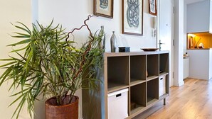 Een moderne woonkamer met een houten kast, een potplant en kunstwerken in een lijst aan de muur.