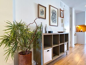 A modern living room with a wooden cabinet, a potted plant, and framed artwork on the wall. - Modern, Open-plan attic apartment, large terrace (Vilanova i la Geltru)