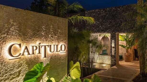 A stone wall with the name 'Capitulo' illuminated, a pathway leading to a building entrance, and tropical plants. - Casa de campo cerca al aeropuerto MDE (Rionegro)