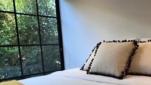 A bed with white linens, two rolled towels with a flower, and a yellow textured blanket. - Casa de campo cerca al aeropuerto MDE (Rionegro)