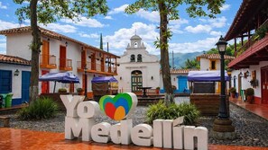 Ein Innenhof mit einem Schild, auf dem 'Yo Medellín' steht, und einer Kirche im Hintergrund.