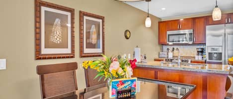 Una cocina moderna con armarios de madera, electrodomésticos de acero inoxidable y una mesa de comedor de cristal con un centro de mesa floral.