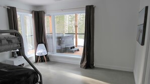 Ein Schlafzimmer mit Bett, Stuhl, Tisch und einem Fenster mit Vorhängen.
