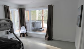 A bedroom with a bed, a chair, a table, and a window with curtains.