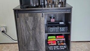 A coffee bar with a sign labeled 'COFFEE BAR' and a shelf with snacks labeled 'LATE NIGHT SNACKS.'