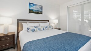 Ett hotellrum med en säng, två sängbord med lampor, ett stort fönster och en inramad tavla på väggen.