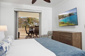 A bedroom with a bed, a dresser, a TV, and a balcony with a table and chairs. - Honua Kai | Ocean View 6 BR, Sleeps 20 | Car Incl. w/ 6+ Nights | HKH ML-2807 by KBM (Lahaina)