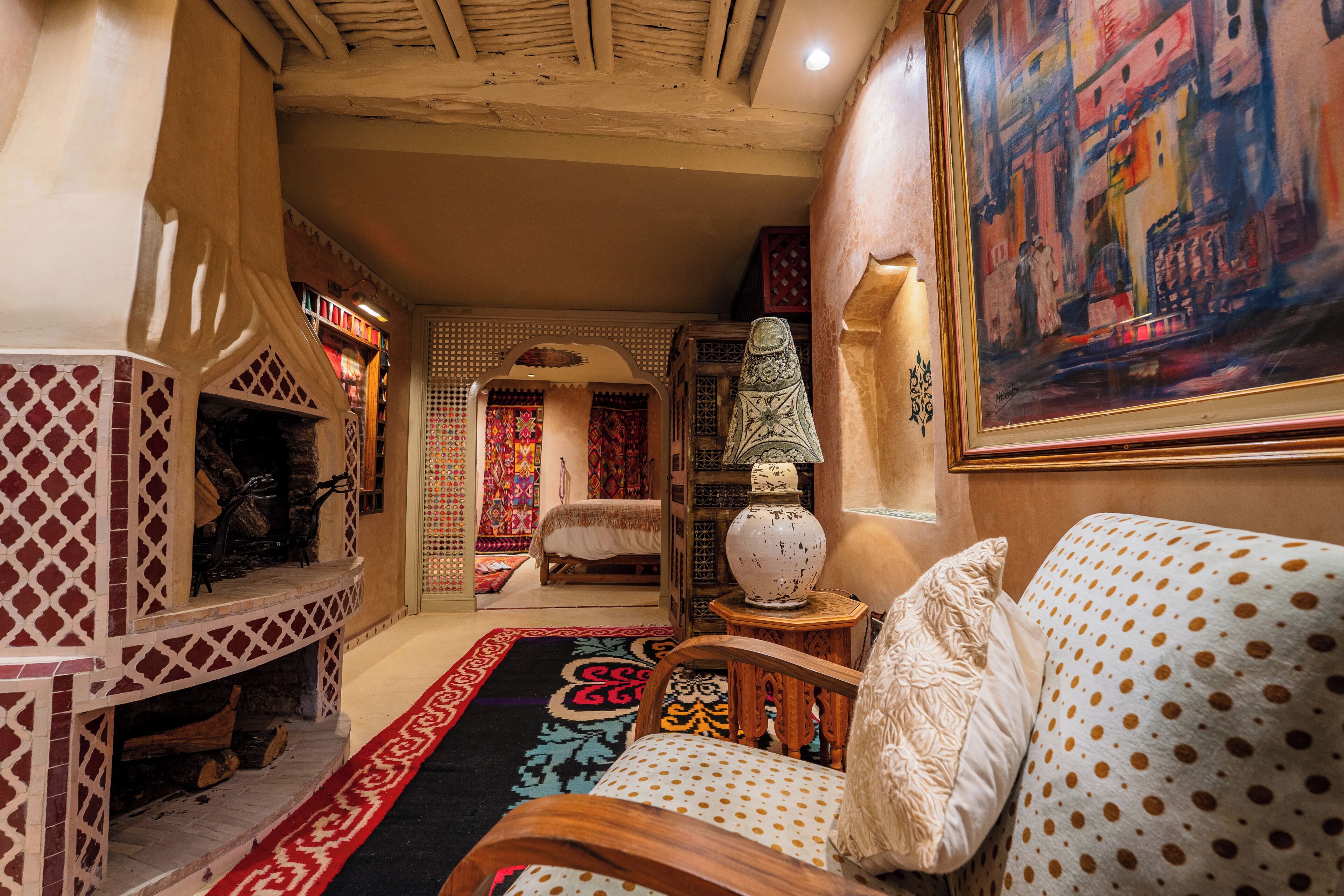 A cozy room with a fireplace, a patterned rug, a sofa with polka dots, and a painting on the wall.