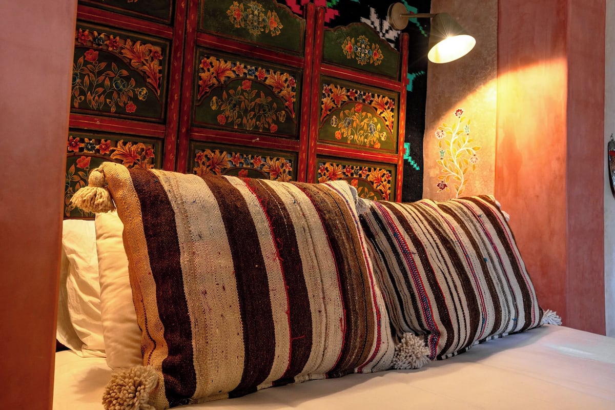 A bed with striped bedding and a decorative headboard with floral patterns.