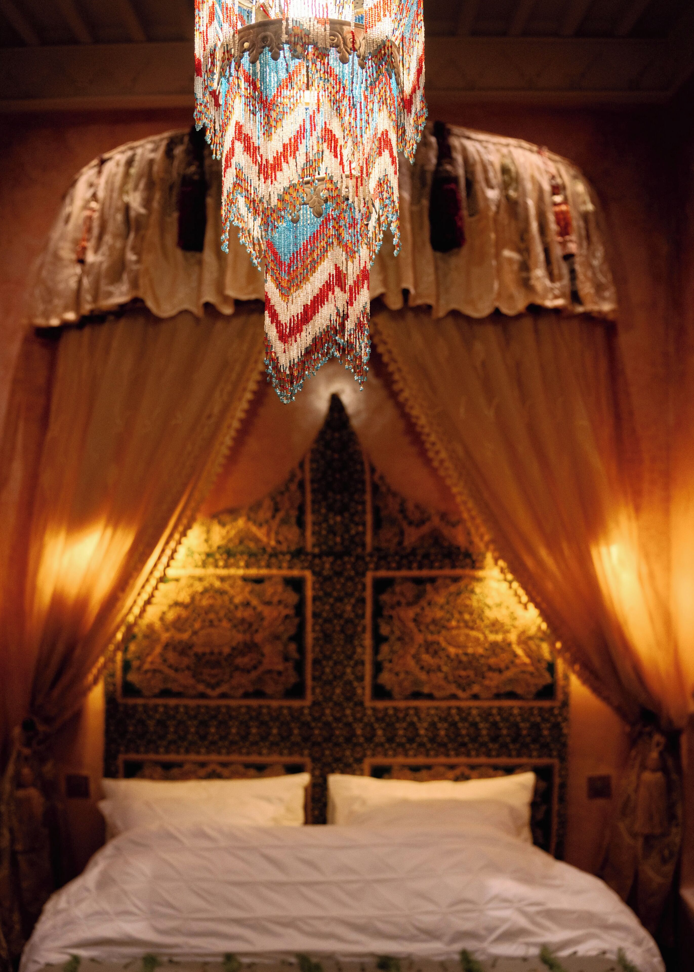 Une chambre avec un lit, une tête de lit à motifs et des rideaux tombants.