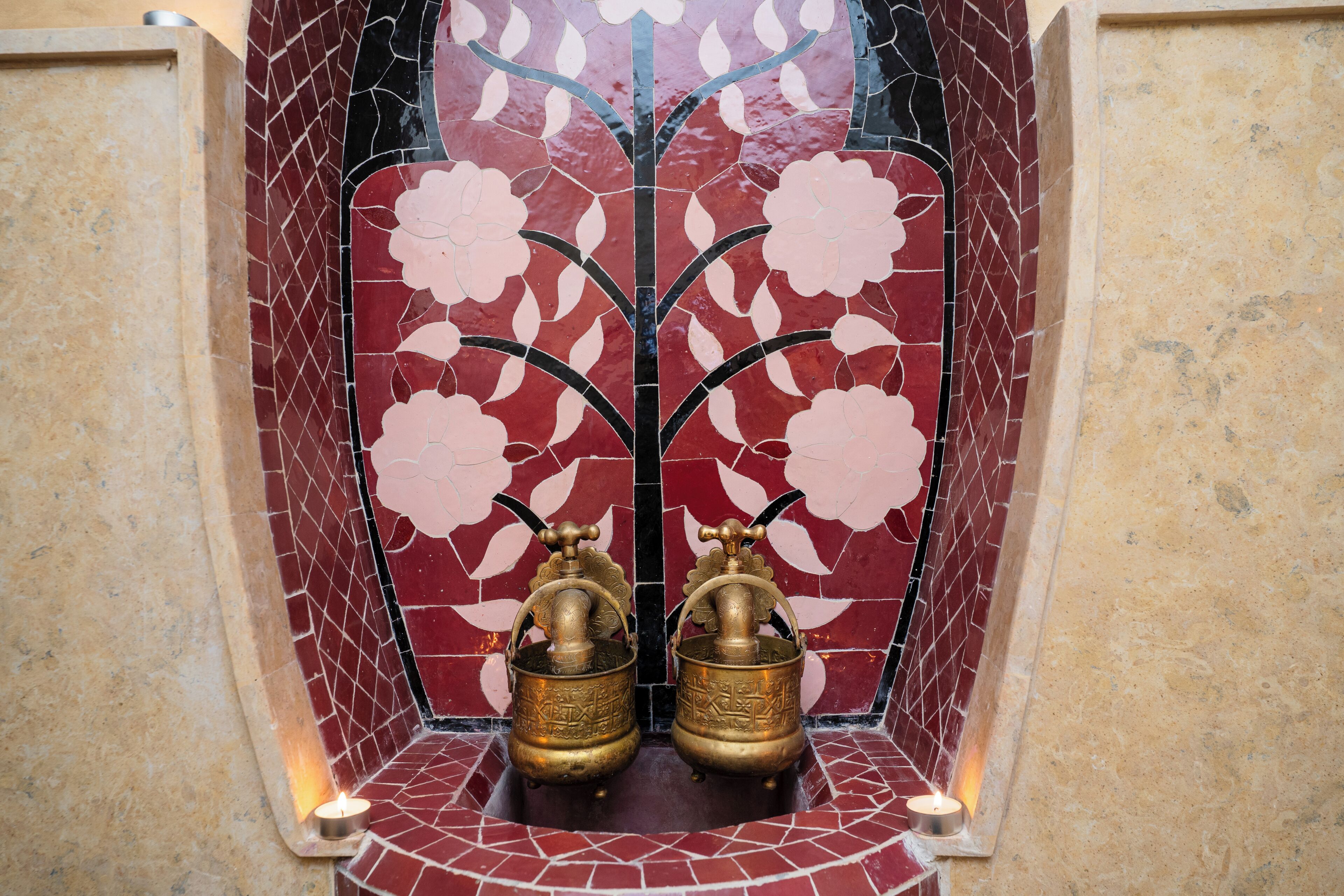 A tiled wall with a floral pattern and two brass objects.