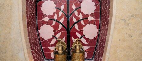 A tiled wall with a floral pattern and two brass objects.