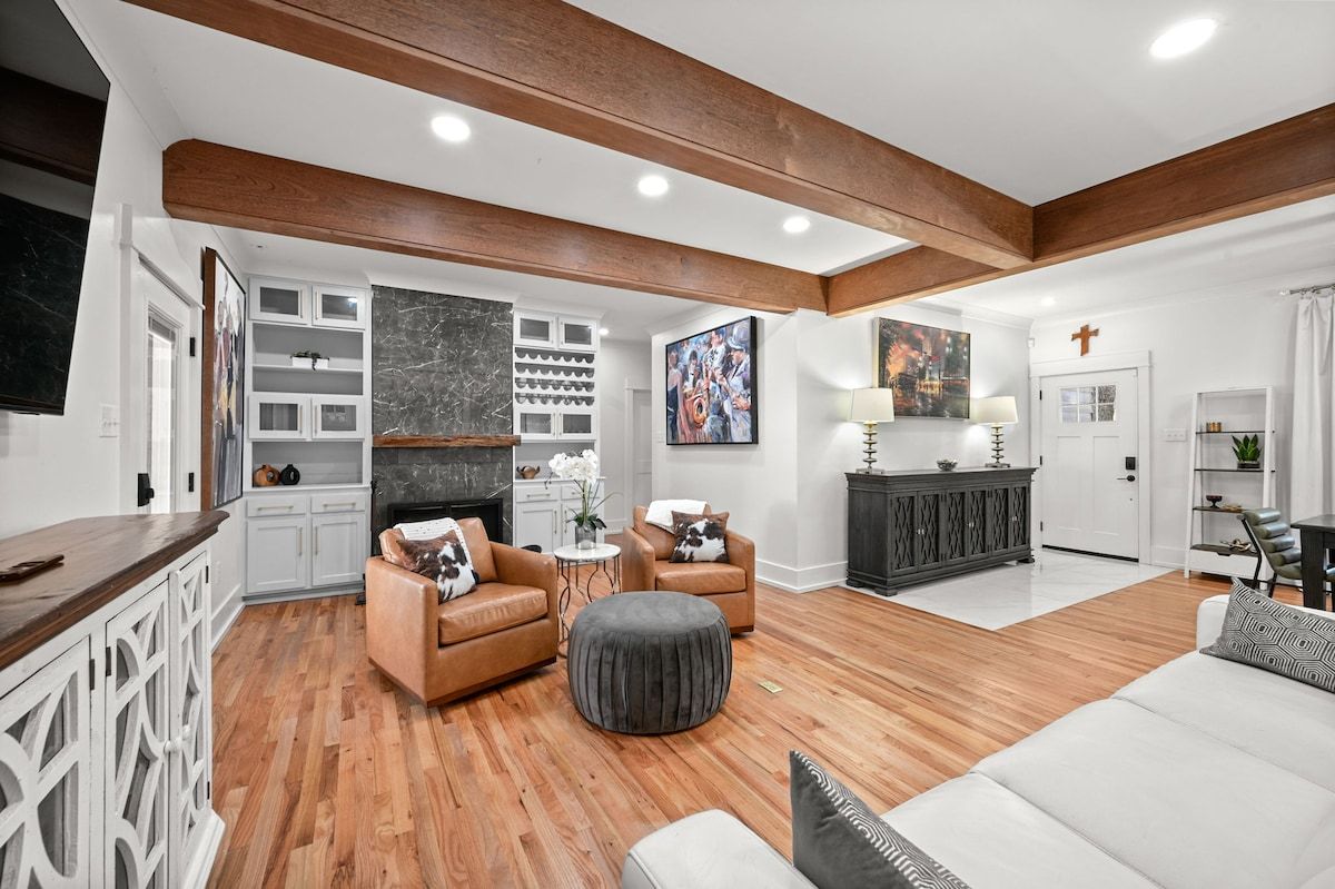 A spacious living room with a fireplace, wooden beams, and a white sofa.