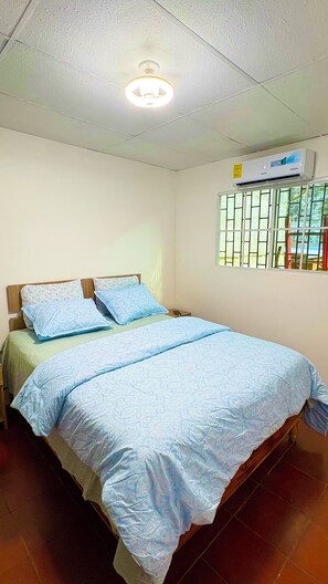 A single bed with a wooden headboard, a window with bars, and an air conditioning unit on the wall. - Fabulous 3-bedroom 2 bath house with AC, gated parking in Santa Ana Department (Santa Ana Department)