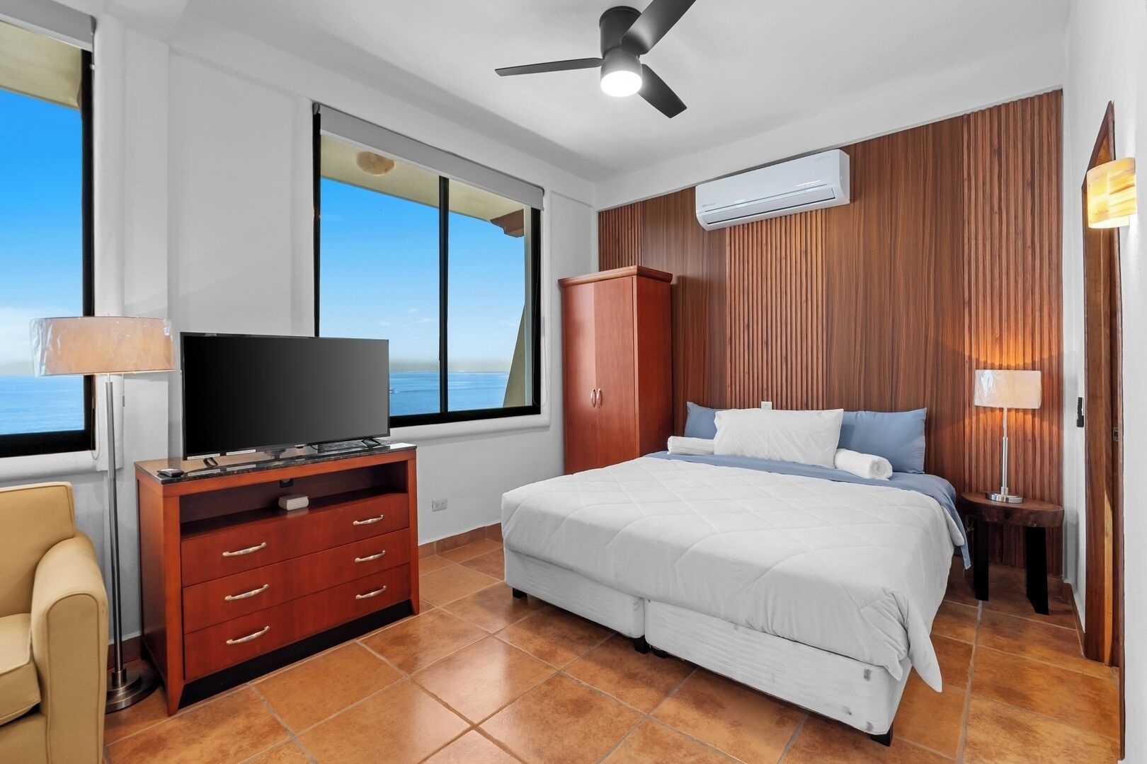 Une chambre d’hôtel équipée d’un lit, d’une télévision, d’une armoire en bois et d’un appareil de climatisation.