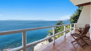 Un balcón con vistas al mar, una mesa y dos sillas.