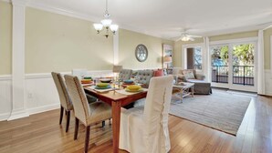 A dining area with a wooden table, chairs, and a chandelier. - Charming Tybee Island Escape on the South End | Heated Pool Access (Tybee Island)