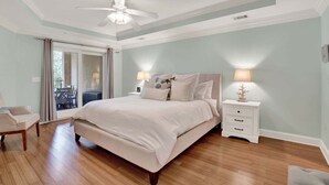 A bedroom with a bed, nightstands, a chair, and a ceiling fan. - Charming Tybee Island Escape on the South End | Heated Pool Access (Tybee Island)