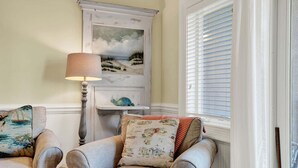 A room with a window, a lamp, and two armchairs with decorative pillows. - Charming Tybee Island Escape on the South End | Heated Pool Access (Tybee Island)