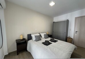 A bedroom with a bed, nightstands, a wardrobe, and a lamp. - Loutra Suites Horizon View (Corinth)