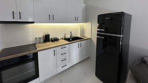 Eine moderne Küche mit weißen Schränken, einem schwarzen Kühlschrank, einer Holz Arbeitsplatte und einer gefliesten Spritzwand.
